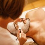 Relaxed man getting facial mask during cosmetic treatment at the spa salon.